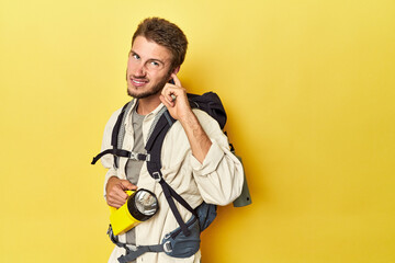 Traveler with mountain backpack and torch covering ears with hands.