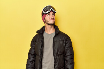 Man in winter coat with snow goggles on yellow dreaming of achieving goals and purposes