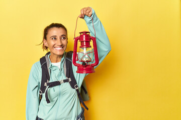 Middle aged woman with mountain backpack and traditional lantern on yellow