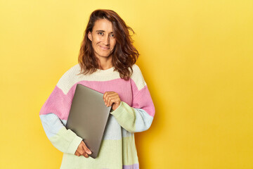 Middle-aged woman using laptop on yellow