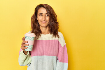 Middle-aged woman with takeaway coffee on yellow