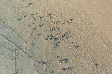 Small rocks and wave marks in the sand. Sea or ocean beach. - 672120935