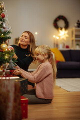 Mother and her little daughter decorating a Christmas tree