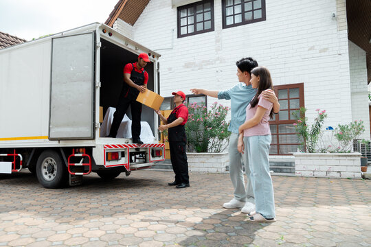 Happy Couple Using Professional Moving House Services Company Deliver To New House, Team Of Mover Workers Carry Boxes, Man And Woman Waiting Uploading Furnitures And Boxes, Shipping Men At Work