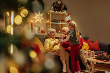 Little girl giving a Christmas present to her grandmother