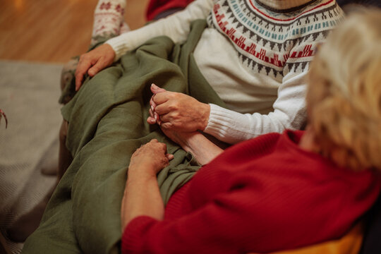 Grandma and grandpa holding hands while sitting on sofa