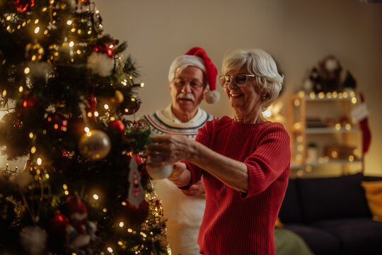 Older couple smiling while decorating a Christmas tree