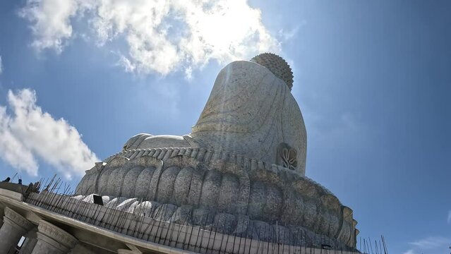 Time warp motion shot of giant Buddha statue in Phuket, Thailand under sunset sky, symbol of peace and meditation