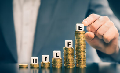 Dice form the German word 'Hilfe' (help) on increasing high stacks of coins. Symbol for financial...