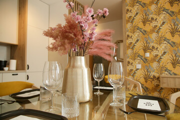 Dining table in the kitchen with pink flowers bouquet in the vase