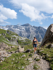 Fototapeta na wymiar Vertical photo of a young adult woman hiking in a stunning mountainous landscape - concept of a healthy lifestyle, well-being, and hiking.