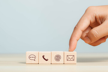 Businessman shows wooden block on icon, contact customer support hotline Contact customers by phone Support online customer support concept Copy space on the computer screen