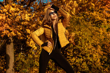 Beautiful woman wearing an winter jacket is posing outdoors on a sunny autumn day.