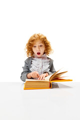 Little redhead, curly girl sitting at desk with emotion of surprise while reading book. Child study and learn for preschool. Online education. Concept of childhood, International Knowledge Day. ad