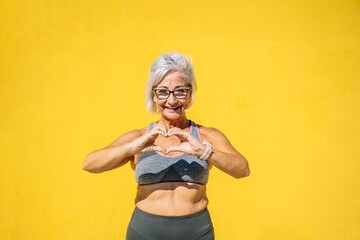 Old sportive woman representing a heart shape with hands