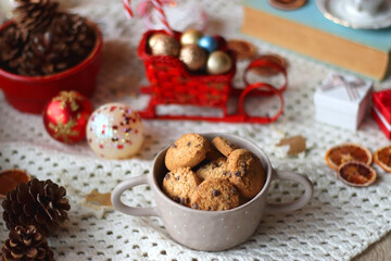 Various colorful Christmas decorations, soft blanket, cup of tea, sweet snacks and lit candles on the table. Cozy Christmas atmosphere at home. Selective focus.