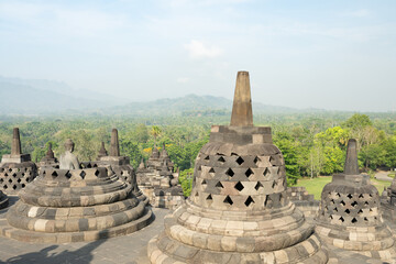(Selective focus) Stunning view of a Buddha Statue in the foreground and some bell shaped stupas in...