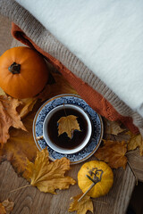 A beautiful cup of tea stands on autumn leaves. Autumn drink. A maple leaf floats in a cup. Autumn mood. Home comfort.