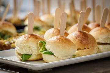 Small buns sandwiches with salad, tomato and meat. Served for an aperitif