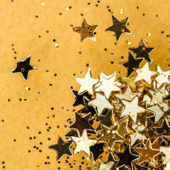Happy New Year celebration. Festive gold background. Shining stars confetti closeup and fairy lights yellow background.