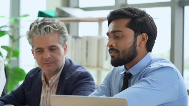 young indian business manager man talking or debate to colleagues in meeting on table with data in office. angry leader presentation explain and answer questions coworker over shoulder