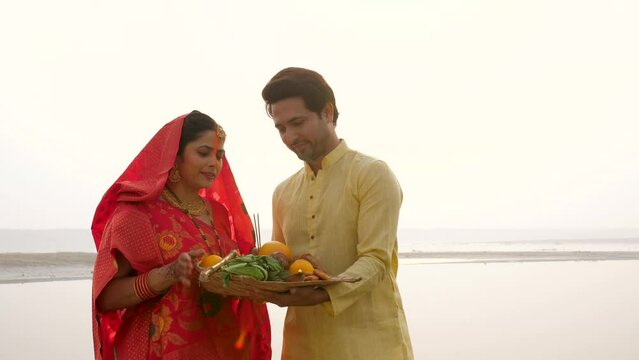 Indian couple preparing their bamboo soop full of Prashad for Chhath Puja - local rituals in Bihar  South Asian couple. Indian married couple from Bihar celebrating chhath puja - worshiping Lord Su...