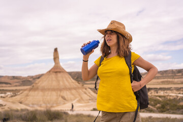 Woman using a reusable bottle of water during a trekking