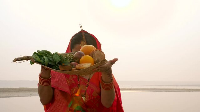 An Indian devotee in traditional attire offers prayers to the sun during the Chhath festival   Asian woman wearing Indian jewelry . An ancient Hindu festival  dedicated to Lord Surya and Chhathi ma...