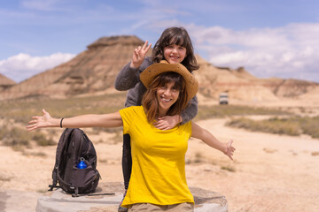 Fototapeta na wymiar Mother and daughter gesturing success after a trekking in a desert