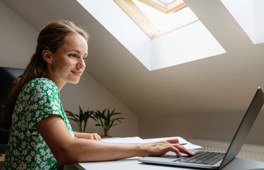 Adult female university student studying at home using e-learning university's platform for the...