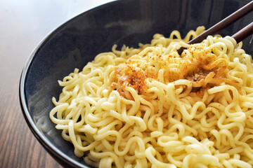 Instant noodles with seasonings on fork in a bowl.