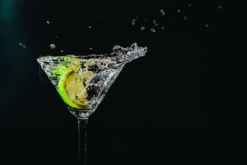 splash in a glass with lime slice on a black background