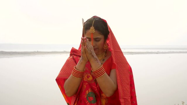 Beautiful women in traditional Indian attire worshiping the Sun God with agarbatti- incense sticks during Chhath puja . Female devotee praying to Sun God during Chhath festival - Bihari Festival  H...