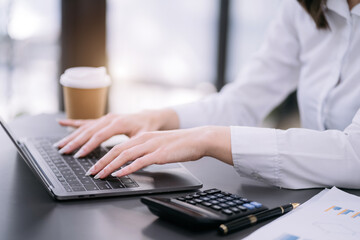 Businesswomen hand working with tablet and laptop computer with documents on office desk in modern office.