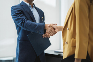 Happy businessman and businesswoman shaking hands at group board meeting. Professional business...