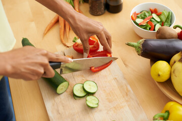Closeup, hands and cutting with vegetables, nutrition and plant based diet in a kitchen. Person,...