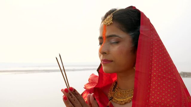 Closeup shot of an Indian female praying to the Sun during Chhath festival with agarbatti - Bihari Festival  Hindu Festival. Female devotee immersed in prayer during the auspicious Chhath festival ...