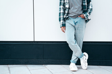 Man in casual street style clothes posing in the street. Model in blue jeans, shirt and sneakers...