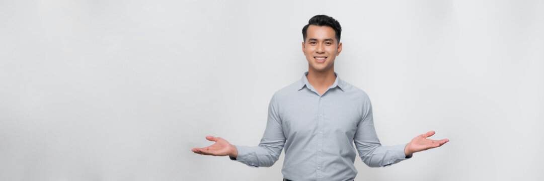 Attractive young Asian man smiling and welcoming heartily with arms open on banner