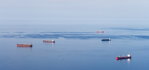Obraz premium Minimalist picture with just the Mediterranean sea, a blue sky and five cargo boats. Oran, Algeria.
