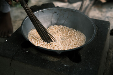 indian way of frying rice in a frypan. healthy indian dry food. stirring with a wooden stick.