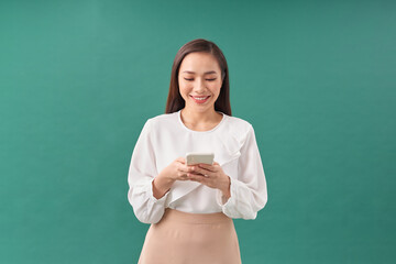 Portrait of a happy asian businesswoman using mobile phone isolated over green background