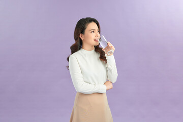 Young woman posing on isolated studio background, hold water glass