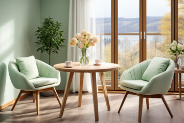 Two mint-colored chairs near a round wooden dining table by the window. Scandinavian interior design for modern dining room