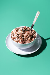 Cereal de granola muesli en un tazón blanco con cuchara sobre fondo verde