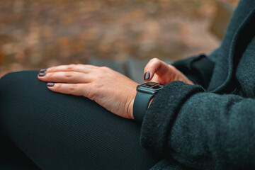 Young woman using smart watch, Girl in autumn park, closeup. High quality photo.