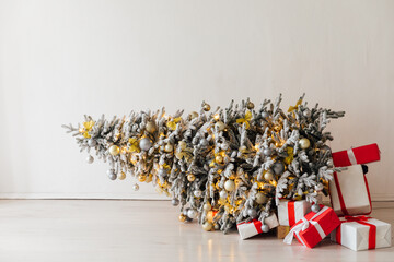 Decorated Christmas tree fallen down. Christmas gifts near fallen tree. Scandinavian Christmas tree.