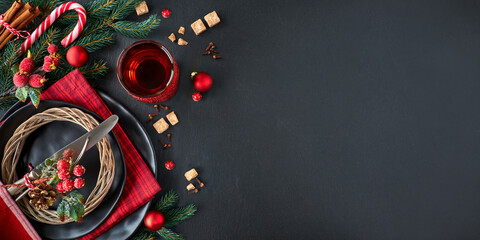 A table with a plate of food and a cup of tea. Christmas menu concept on dark stone slate, text space