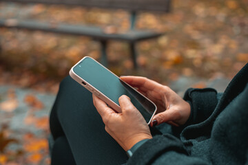 City lifestyle stylish  using a phone texting on smartphone app in a street. Young woman with...