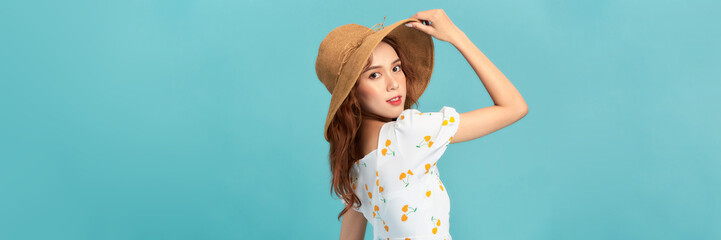 Beautiful smiling young woman in summer straw hat isolated on pastel blue background.